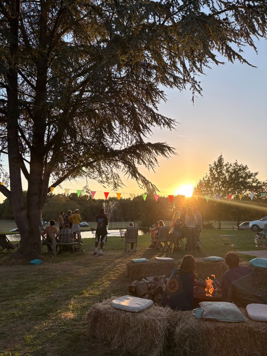 Sunset over the lawn, with hay bales and cushions under the big cedar