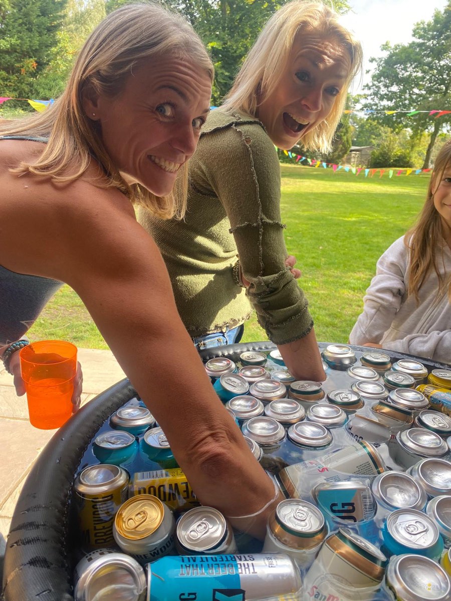 Two friends grinning over a tub of cold drinks