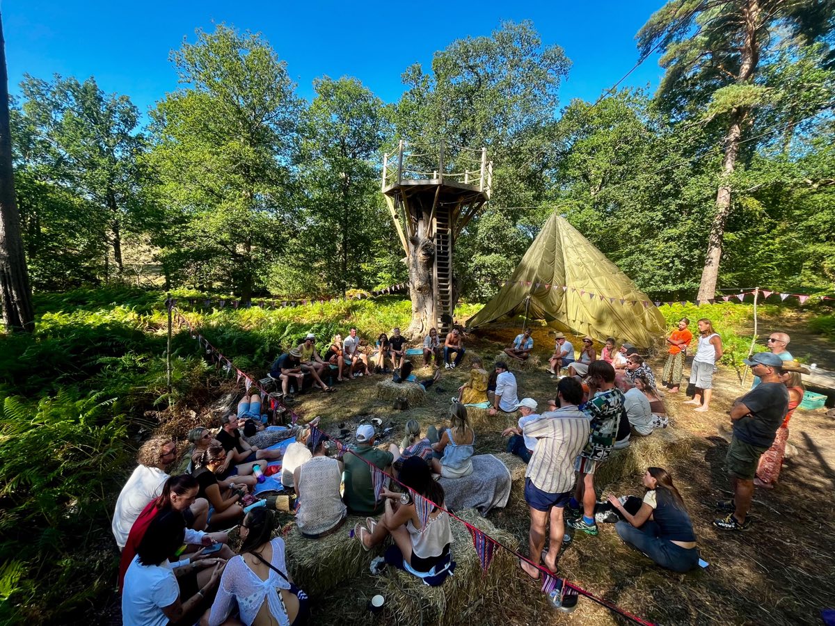 The parachute area by day: everyone sat in a circle in the woods by the treehouse tower
