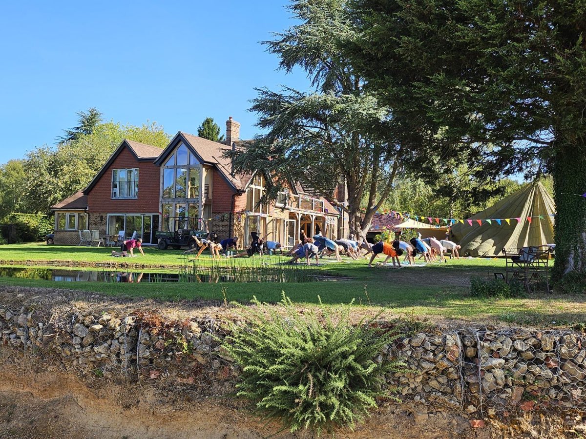 A yoga class on the lawn in front of the house, with bunting strung to a bell tent under the big cedar